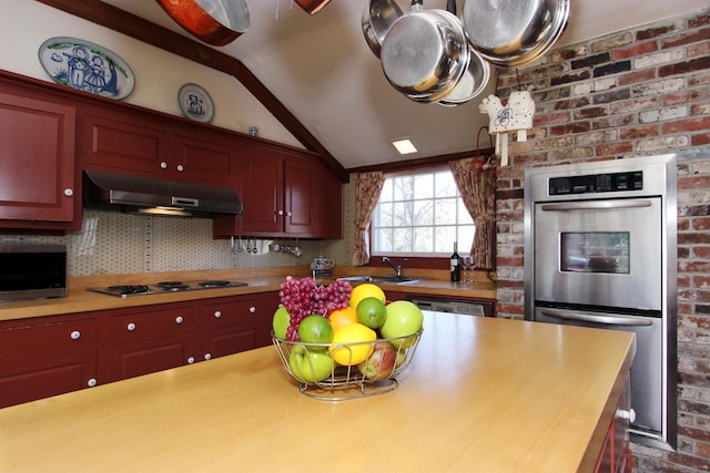 kitchen with appliances with stainless steel finishes, sink, exhaust hood, decorative backsplash, and lofted ceiling