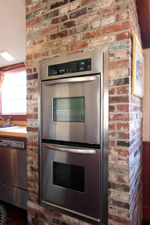 kitchen featuring brick wall and appliances with stainless steel finishes