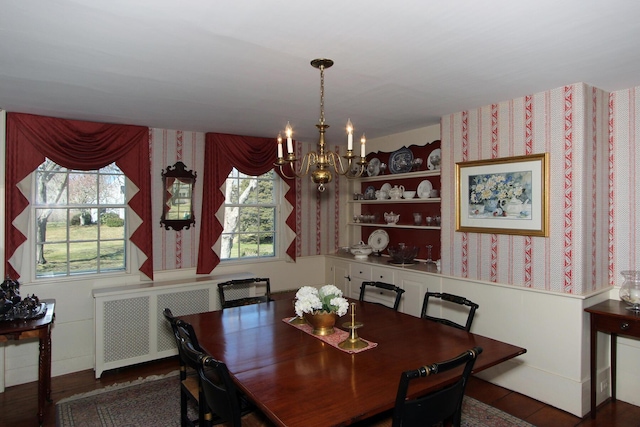 dining space with dark wood-type flooring, radiator, a wealth of natural light, and an inviting chandelier