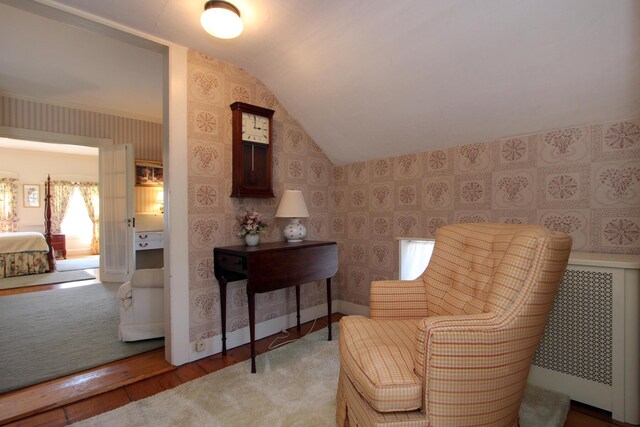 living area with vaulted ceiling, radiator, and light wood-type flooring