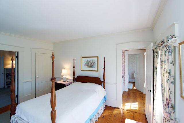 bedroom with a closet, light wood-type flooring, and ornamental molding