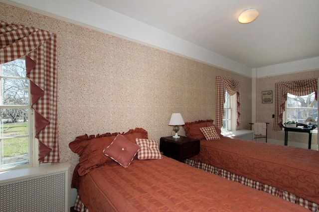 bedroom featuring radiator heating unit and multiple windows