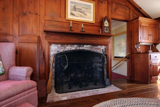 room details featuring hardwood / wood-style flooring, a brick fireplace, and wooden walls