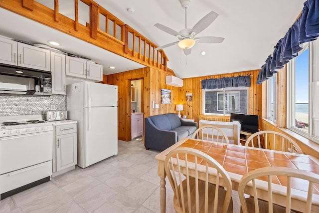 kitchen featuring ceiling fan, white appliances, a wall unit AC, white cabinets, and wood walls