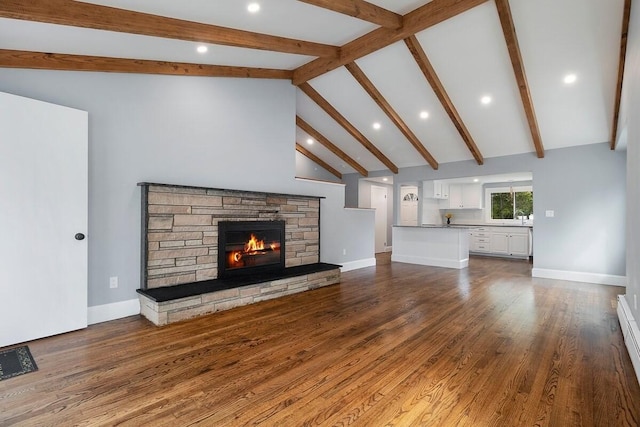 unfurnished living room featuring dark wood-type flooring, beamed ceiling, a stone fireplace, sink, and high vaulted ceiling