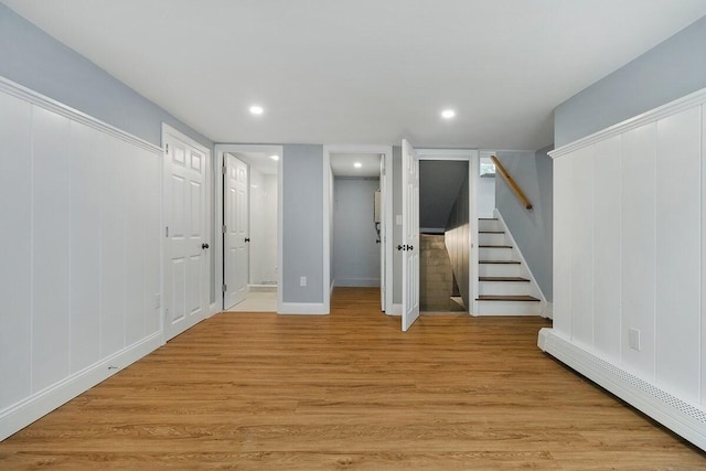 basement featuring light hardwood / wood-style floors and a baseboard heating unit