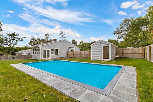 view of pool with a lawn and a storage unit