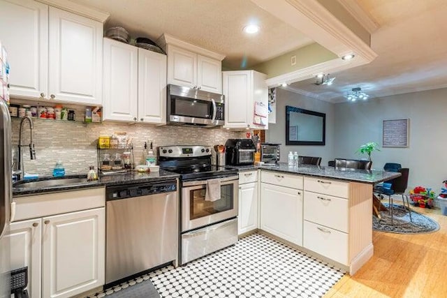 kitchen featuring stainless steel appliances, decorative backsplash, white cabinets, and kitchen peninsula