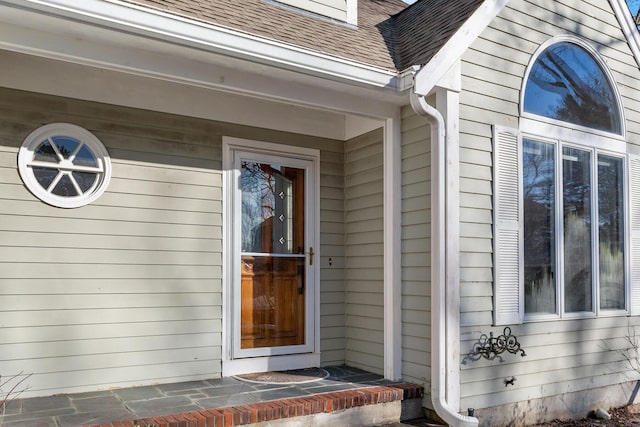 doorway to property featuring a shingled roof