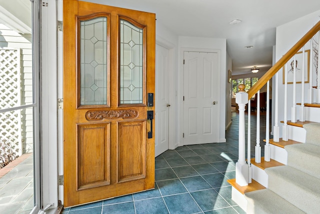 entrance foyer with dark tile patterned floors and stairs