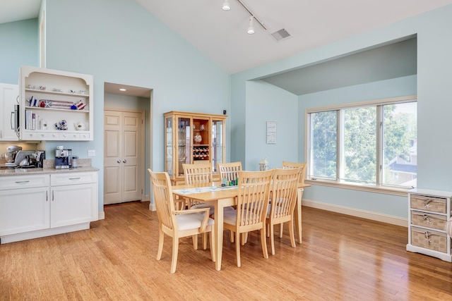 dining room featuring light hardwood / wood-style floors, high vaulted ceiling, and track lighting