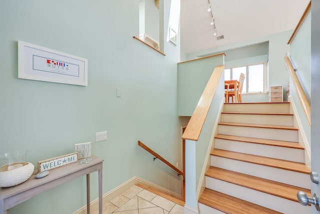 staircase featuring tile patterned floors and rail lighting