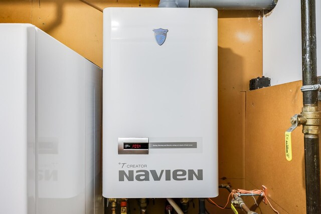 utility room featuring tankless water heater and water heater