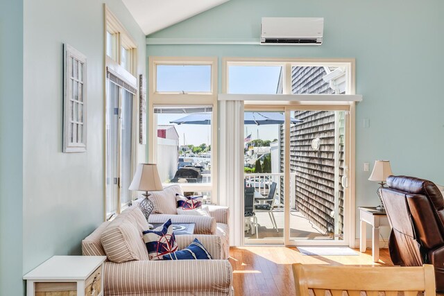 interior space with light hardwood / wood-style floors, lofted ceiling, and a wall mounted air conditioner