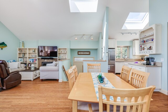 dining area featuring light hardwood / wood-style floors and lofted ceiling with skylight