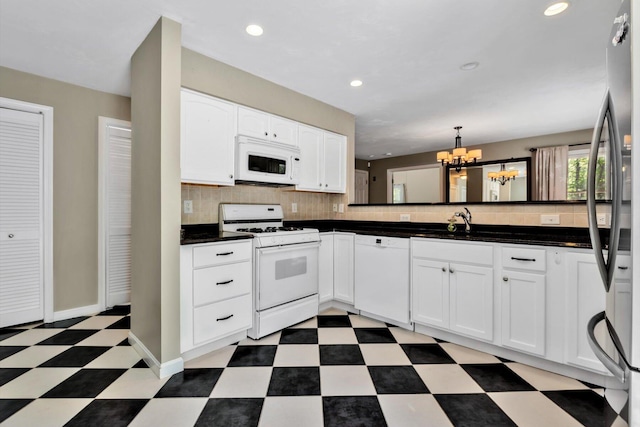 17 Greenway Cir, Sandwich, MA 02563 - kitchen featuring white appliances, light flooring, a chandelier, dark countertops, and tasteful backsplash