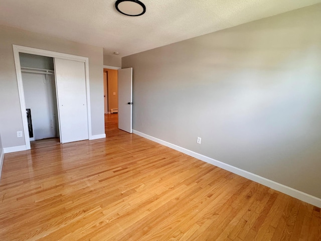 unfurnished bedroom featuring a textured ceiling, a closet, and light wood-type flooring