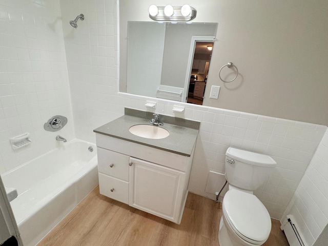 full bathroom featuring baseboard heating, tiled shower / bath combo, vanity, tile walls, and hardwood / wood-style flooring