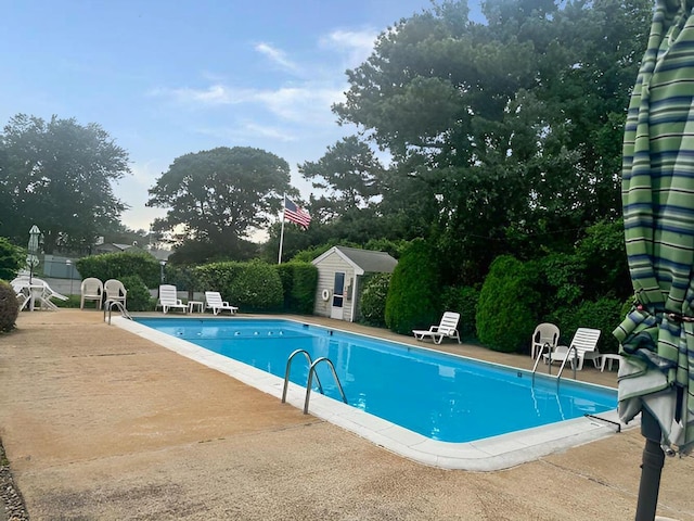 view of pool featuring a patio and an outbuilding