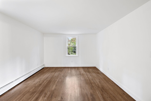 empty room featuring dark wood-type flooring and a baseboard heating unit