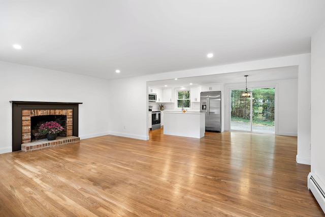 unfurnished living room with light hardwood / wood-style floors, a baseboard radiator, and a fireplace