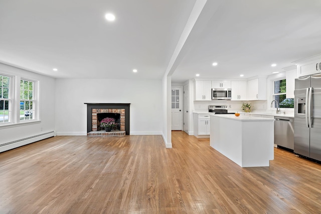 kitchen with white cabinets, stainless steel appliances, a kitchen island, and a fireplace