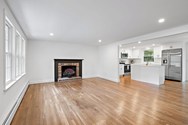 unfurnished living room with light hardwood / wood-style floors, a baseboard radiator, and a fireplace