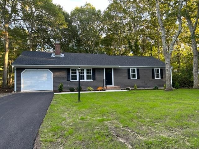 ranch-style house featuring a garage and a front lawn