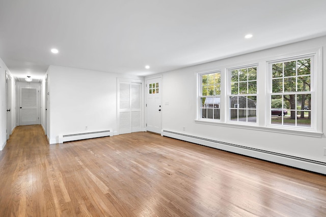 unfurnished living room with a baseboard radiator and light wood-type flooring