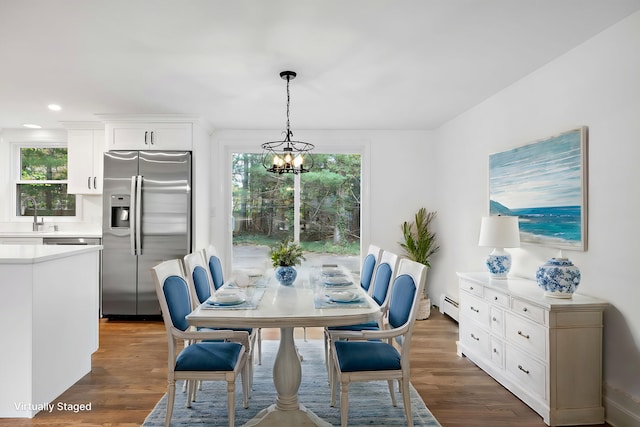 dining room with a baseboard radiator, dark wood-type flooring, and an inviting chandelier