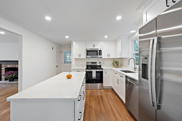 kitchen featuring sink, stainless steel appliances, white cabinetry, and a center island