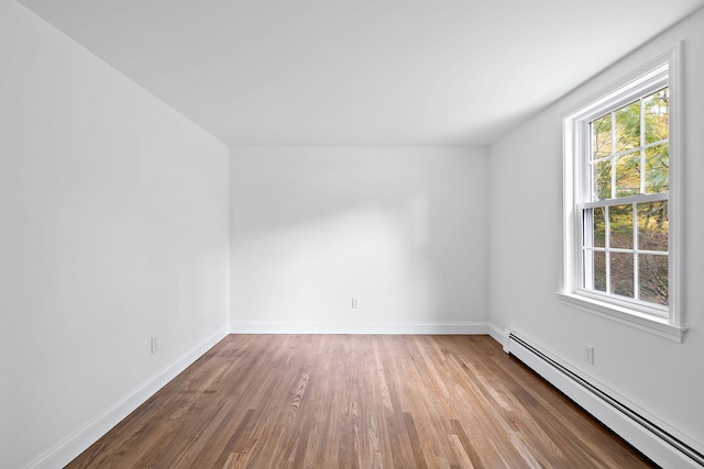 unfurnished room featuring hardwood / wood-style flooring and a baseboard heating unit