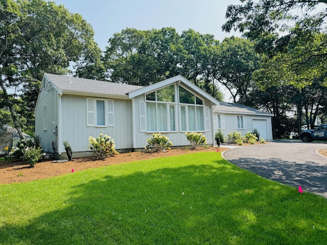 131 Portside Cir E, Falmouth, MA 02536 - view of front of house featuring asphalt driveway, a front yard, a garage, and roof with shingles