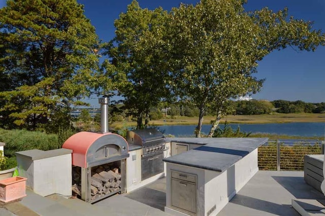 view of patio / terrace featuring a water view, area for grilling, and exterior kitchen