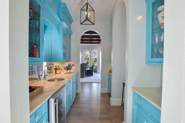 bar with sink, blue cabinetry, and decorative light fixtures