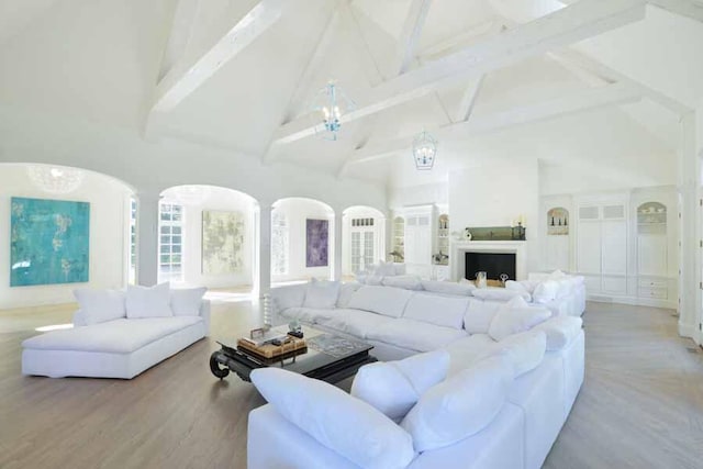 living room with beam ceiling, light wood-type flooring, and high vaulted ceiling