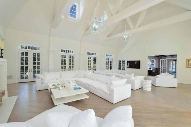 living room featuring beamed ceiling, a chandelier, high vaulted ceiling, and french doors