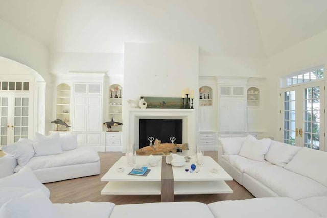 living room featuring a high ceiling, wood-type flooring, built in features, and french doors