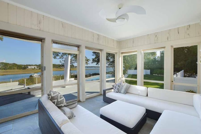 sunroom featuring ceiling fan and a water view