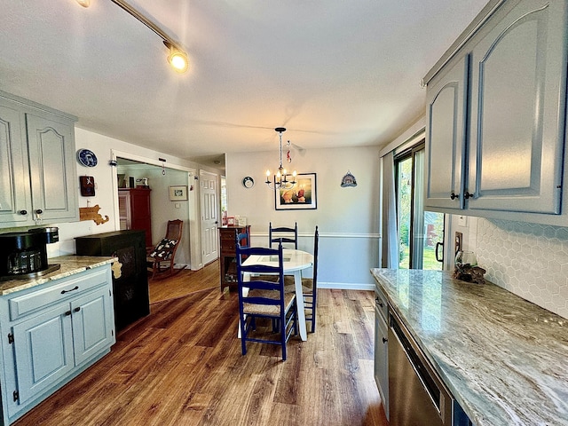 kitchen featuring pendant lighting, dishwasher, dark wood-type flooring, decorative backsplash, and a chandelier