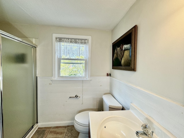 bathroom featuring toilet, a textured ceiling, and an enclosed shower