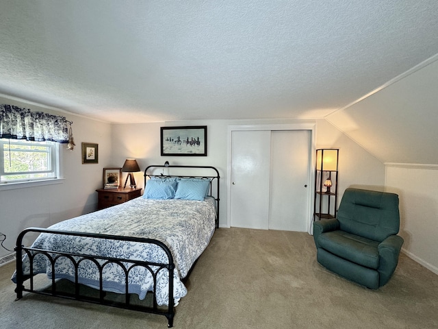 bedroom featuring a closet, carpet flooring, a textured ceiling, and lofted ceiling