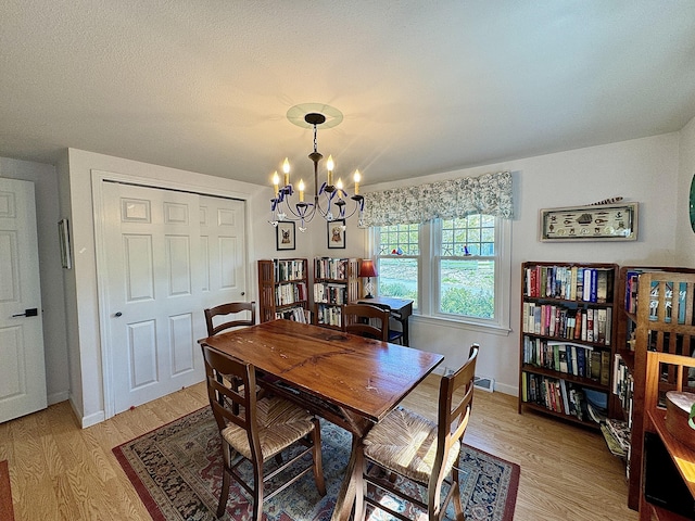 dining area featuring light wood-type flooring and a notable chandelier