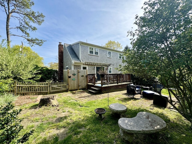 back of house featuring a lawn and a wooden deck