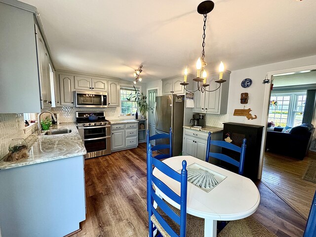 kitchen with sink, decorative light fixtures, backsplash, dark wood-type flooring, and stainless steel appliances