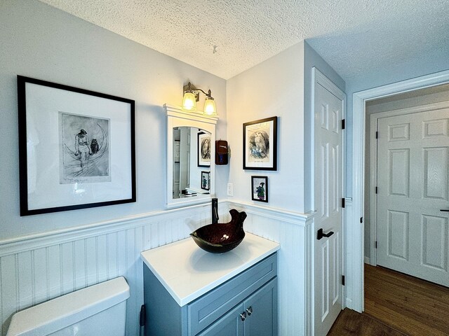 bathroom with hardwood / wood-style floors, a textured ceiling, toilet, and vanity