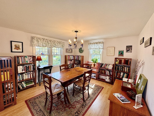 dining area featuring a textured ceiling, light hardwood / wood-style flooring, and an inviting chandelier