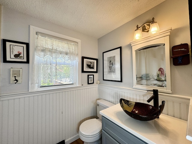 bathroom with vanity, toilet, and a textured ceiling