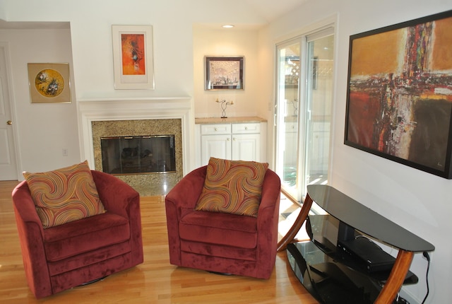 sitting room featuring a premium fireplace, light wood-type flooring, and a healthy amount of sunlight