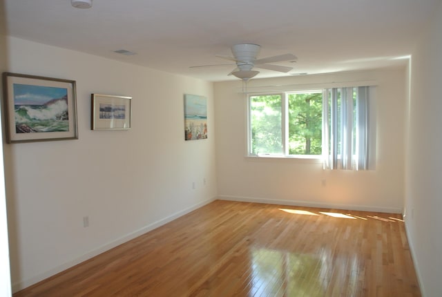 empty room with ceiling fan and light hardwood / wood-style flooring